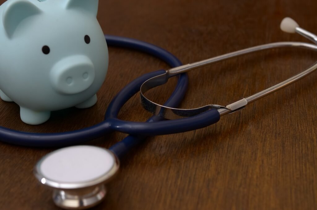 Blue piggy bank with medical stethoscope on wooden surface for healthcare costs concept