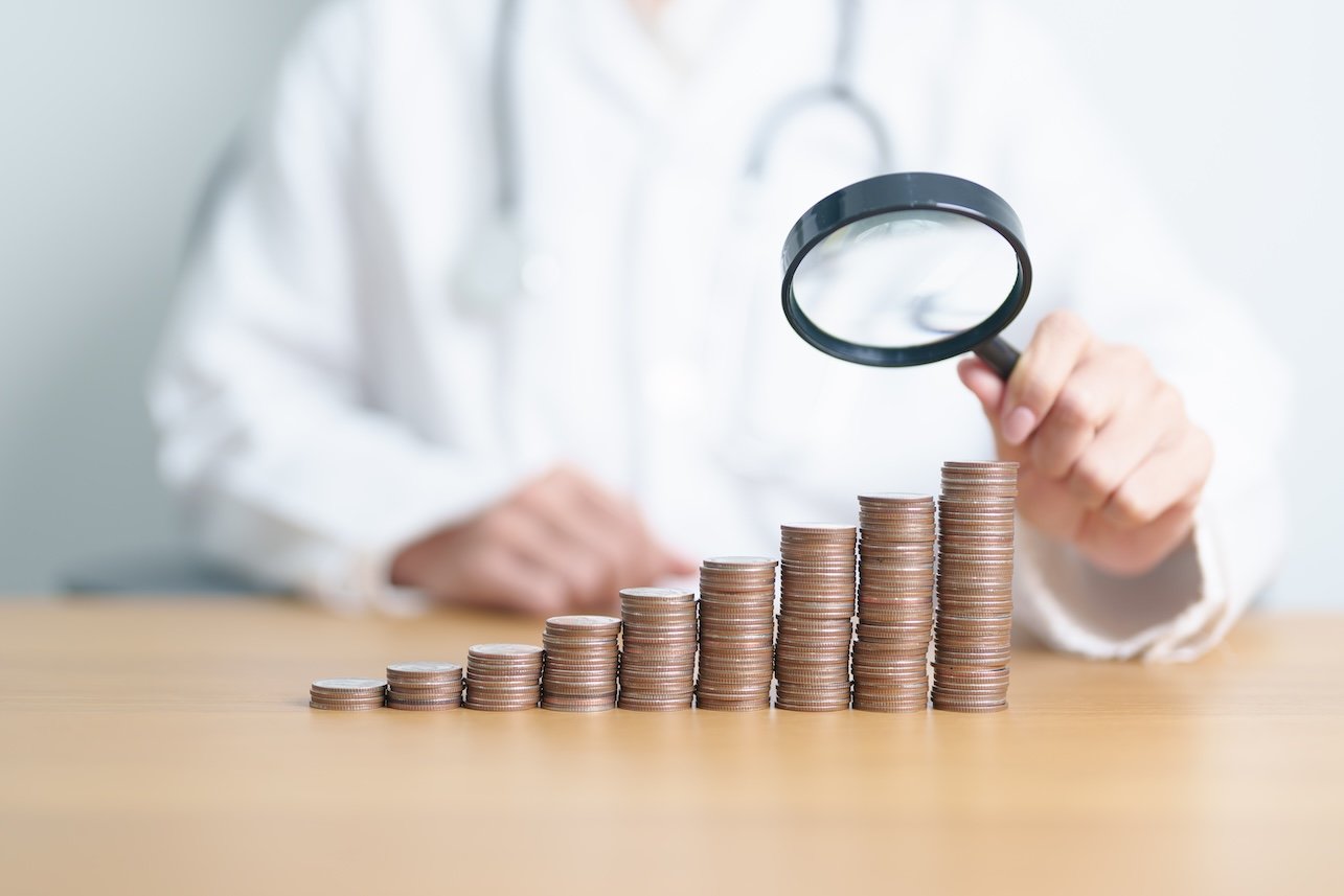 Doctor with Coins money stack growing with magnifier glass. Money saving, Job search, hiring and research development, Health Insurance, Medical, Donation and Healthcare cost concepts